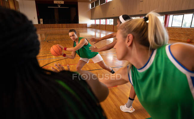 Equipe de basquete feminina diversa vestindo roupas esportivas e praticar driblando bola. basquete, treinamento esportivo em uma quadra interna. — Fotografia de Stock