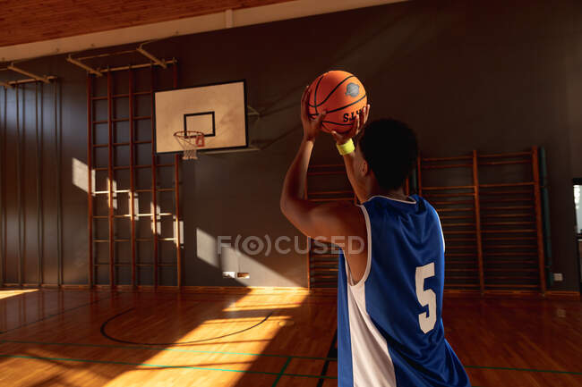 Mixte joueur de basket-ball masculin pratiquant le tir avec balle. basket-ball, entraînement sportif sur un terrain intérieur. — Photo de stock