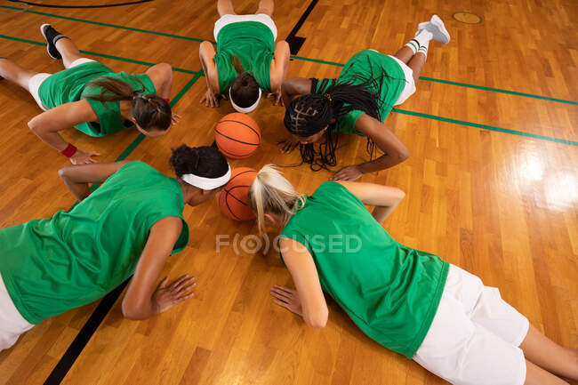 Різноманітна жіноча баскетбольна команда носить спортивний одяг і робить поштовхи. баскетбол, спортивне тренування в критому дворі . — стокове фото