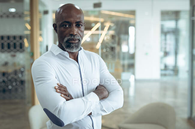 Porträt eines afrikanisch-amerikanischen Geschäftsmannes, der mit verschränkten Armen in die Kamera blickt. Arbeit in einem unabhängigen kreativen Unternehmen. — Stockfoto