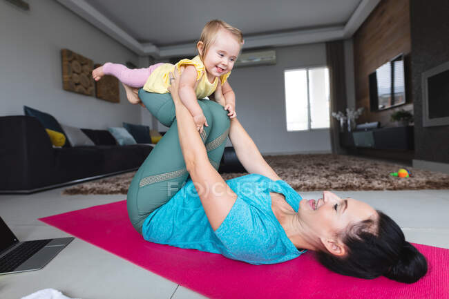 Mère blanche tenant son bébé et faisant du yoga à la maison. concept de maternité, d'amour et de soins pour bébé — Photo de stock