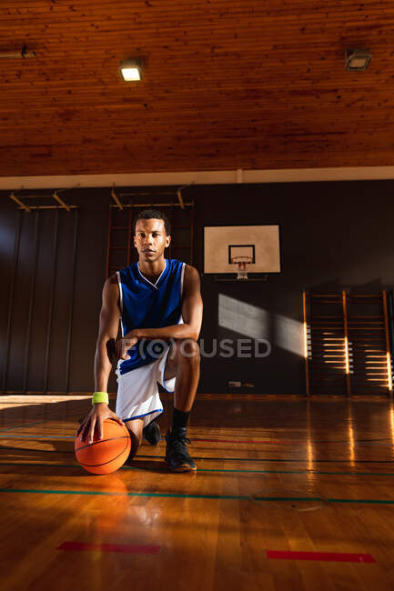Portrait d'un joueur afro-américain de basket-ball tenant le ballon. basket-ball, entraînement sportif sur un terrain intérieur. — Photo de stock