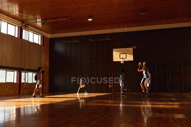 Diverse male basketball team practicing shooting with ball. basketball, sports training at an indoor court. — Stock Photo