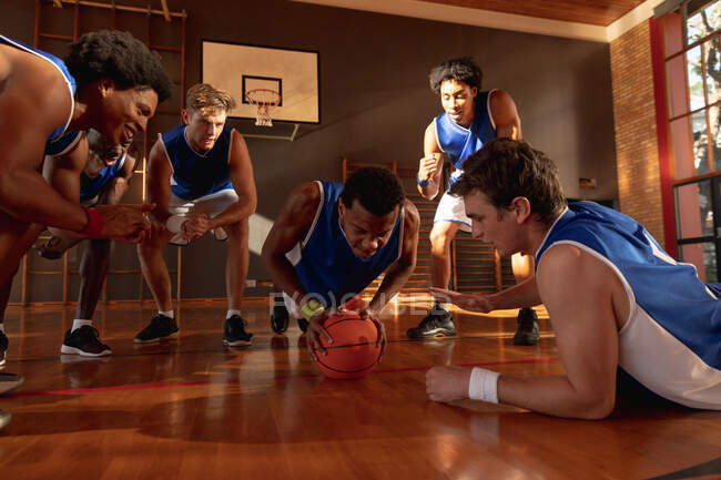 Diverse male basketball team wearing blue sportswear and doing push ups. basketball, sports training at an indoor court. — Stock Photo