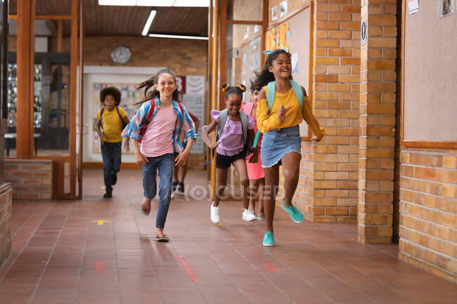Grupo de estudiantes diversos corriendo juntos en el pasillo de la escuela. escuela y concepto de educación - foto de stock