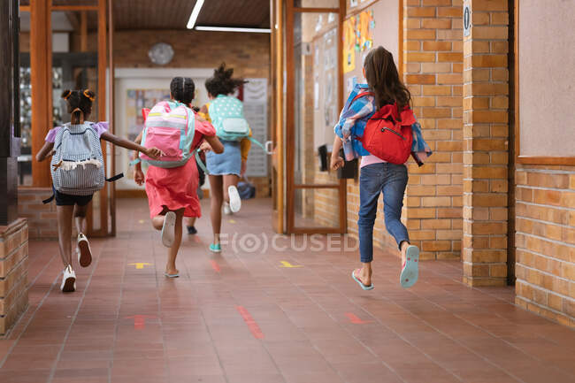 Rückansicht einer Mädchengruppe, die auf dem Schulflur läuft. Schul- und Bildungskonzept — Stockfoto