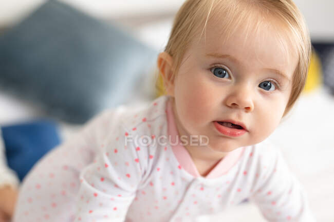 Portrait of caucasian baby sitting on the bed at home. motherhood, love and baby care concept — Stock Photo