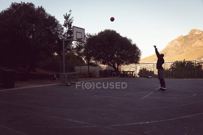 Afrikanischer männlicher Basketballspieler beim Schießen mit Ball. Basketball, Sporttraining auf einem städtischen Außenplatz. — Stockfoto