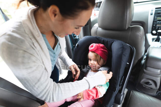 Mère caucasienne mettant son bébé en sécurité siège bébé dans la voiture. concept de maternité, d'amour et de soins pour bébé — Photo de stock