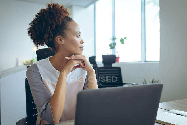 Gemischte Rasse Geschäftsfrau sitzt am Schreibtisch mit Laptop-Denken. Isolationshaft während der Quarantäne. — Stockfoto
