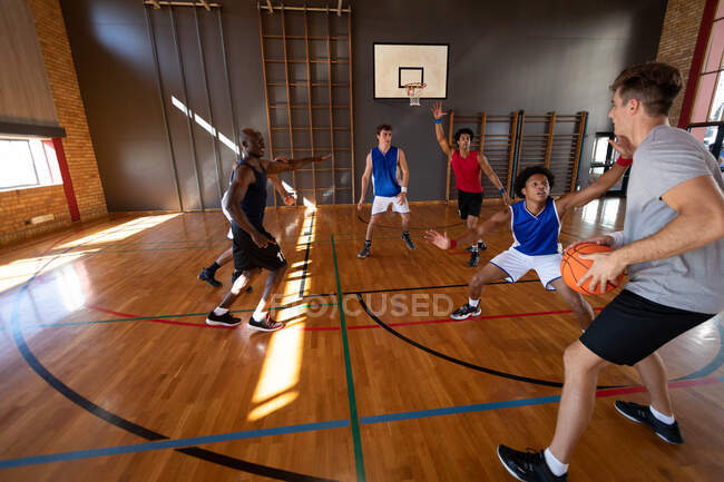 Equipe de basquete masculino diverso e treinador jogando jogo. basquete, treinamento esportivo em uma quadra interna. — Fotografia de Stock