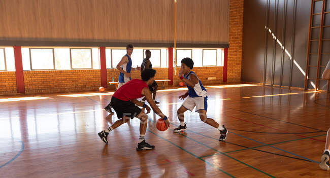 Разнообразная мужская баскетбольная команда и тренер играют матч. баскетбол, спортивные тренировки на крытой площадке. — стоковое фото