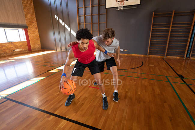 Deux joueurs masculins différents pratiquent le dribble ball. basket-ball, entraînement sportif sur un terrain intérieur. — Photo de stock