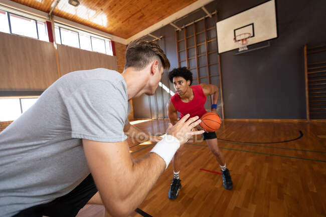 Zwei unterschiedliche männliche Basketballspieler üben sich im Dribbeln. Basketball, Sporttraining auf einem Indoor-Court. — Stockfoto