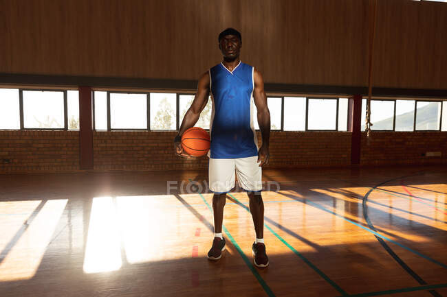 Portrait of african american male basketball player holding ball. basketball, sports training at an indoor court. — Stock Photo