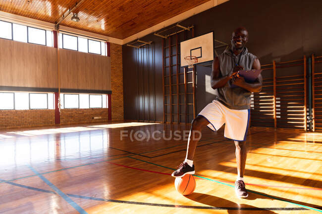 Retrato del entrenador de baloncesto afroamericano con pelota. baloncesto, entrenamiento deportivo en una cancha cubierta. - foto de stock