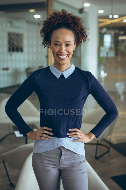 Ritratto di donna d'affari mista che sorride, guardando la macchina fotografica con l'ufficio sullo sfondo. lavorare in un'attività creativa indipendente. — Foto stock