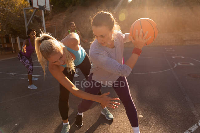 Equipe de basquete feminina diversa vestindo roupas esportivas e praticar driblando bola. basquete, treinamento esportivo em um campo urbano ao ar livre. — Fotografia de Stock