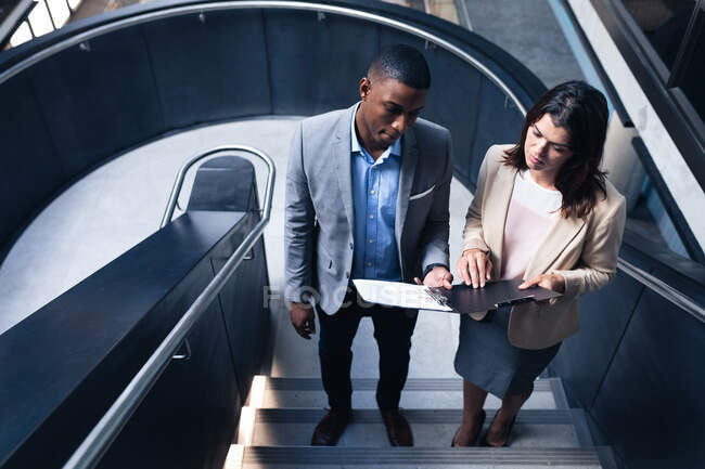 Різноманітний бізнесмен і бізнес-леді обговорюють разом, стоячи на сходах в офісі. бізнес та офісна концепція — стокове фото