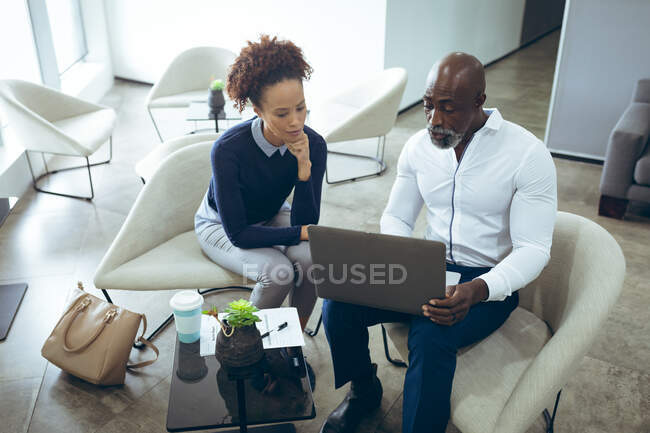 Дві різні чоловічі та жіночі бізнес-колеги сидять та використовують ноутбук. робота в незалежному творчому бізнесі . — стокове фото