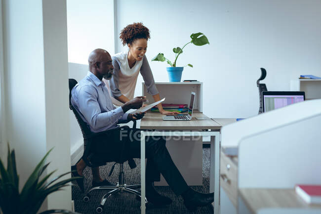 Zwei unterschiedliche männliche und weibliche Kollegen, die am Schreibtisch sitzen und Laptop benutzen. Arbeit in einem unabhängigen kreativen Unternehmen. — Stockfoto