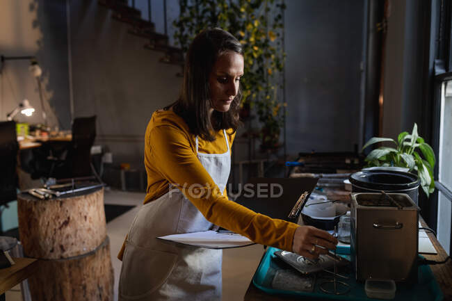 Кавказька жінка-ювелір стоїть у майстерні, готуючи матеріали для ювелірних виробів. Незалежний ремісничий бізнес. — стокове фото