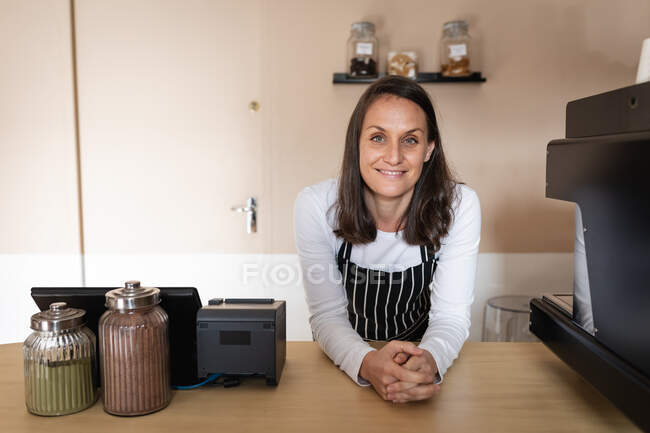 Smiling caucasian business owner standing at counter top and looking at camera. small independent cafe business. — Stock Photo