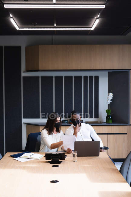 Diverse businessman and businesswoman wearing face masks discussing over a document at office. hygiene and social distancing in the workplace during coronavirus covid-19 pandemic — Stock Photo