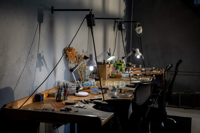 Diversos ferramentas de joalharia, lâmpadas e outros utensílios deitados na mesa em oficina. negócios artesanais independentes. — Fotografia de Stock