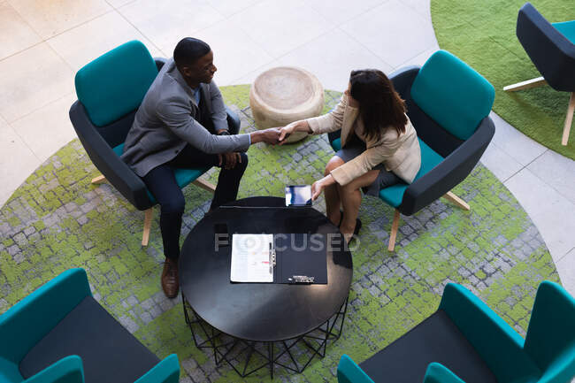 Вид сверху на разнообразных бизнесменов и деловых женщин, пожимающих руки в современном офисе. бизнес и офисная концепция — стоковое фото