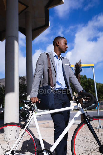 Un premuroso uomo d'affari afroamericano con una bicicletta in piedi in un parco aziendale. concetto di business e ufficio — Foto stock