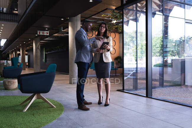 Diverse businessman and businesswoman discussing over digital tablet at modern office. business and office concept — Stock Photo