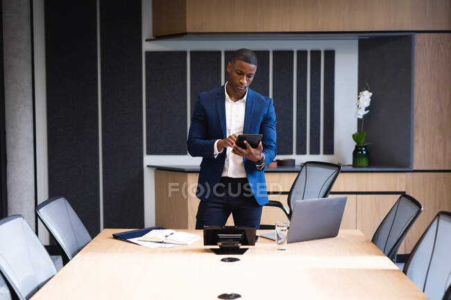 Hombre de negocios afroamericano usando tableta digital en la sala de reuniones en la oficina. concepto de negocio y oficina - foto de stock