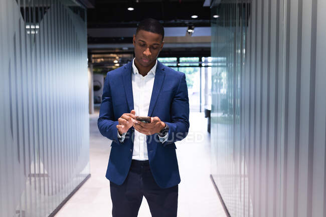 Африканский американский бизнесмен использует смартфон, стоя в современном офисе. бизнес и офисная концепция — стоковое фото