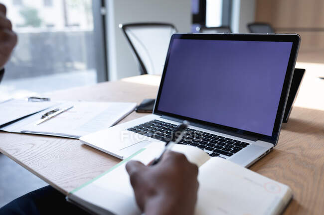 Seção média de homem de negócios com laptop tomando notas enquanto sentado na sala de reuniões no escritório moderno. conceito de negócio e escritório — Fotografia de Stock