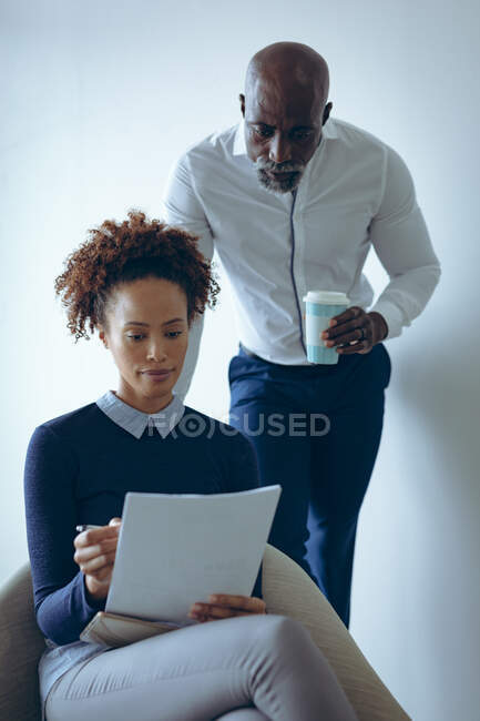 Zwei unterschiedliche männliche und weibliche Geschäftskollegen sitzen und halten Dokumente in der Hand. Arbeit in einem unabhängigen kreativen Unternehmen. — Stockfoto