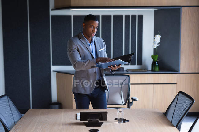 African american businessman reading documents while standing in meeting room at modern office. business and office concept — Stock Photo