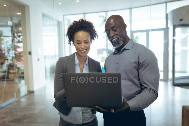 Zwei unterschiedliche männliche und weibliche Business-Kollegen mit Laptop und lächelnd. Arbeit in einem unabhängigen kreativen Unternehmen. — Stockfoto