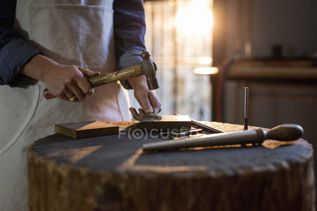 Midsection of female jeweller holding jewelry tools, making jewelry in workshop. independent handmade craft business. — Stock Photo