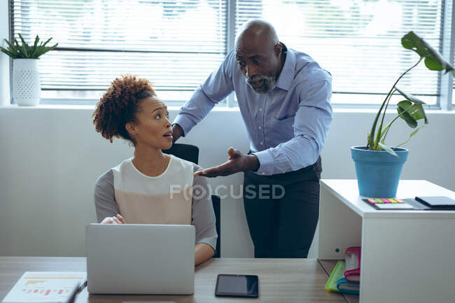 Deux collègues d'affaires masculins et féminins divers assis au bureau et utilisant un ordinateur portable. travailler dans une entreprise créative indépendante. — Photo de stock