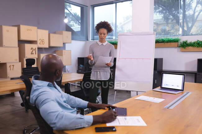 Zwei unterschiedliche männliche und weibliche Kollegen sitzen am Schreibtisch und diskutieren. Arbeit in einem unabhängigen kreativen Unternehmen. — Stockfoto