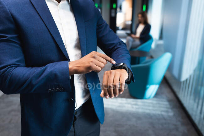 Der mittlere Teil der Geschäftsleute nutzt die Smartwatch im modernen Büro. Geschäfts- und Bürokonzept — Stockfoto