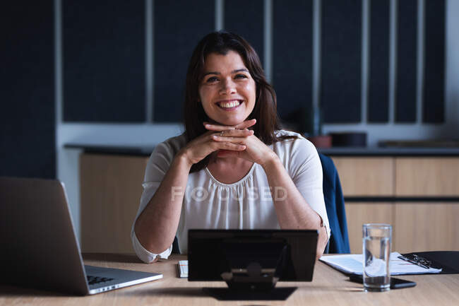 Портрет кавказької бізнес-леді, яка посміхається, сидячи в кімнаті для переговорів в сучасному офісі. бізнес та офісна концепція — стокове фото
