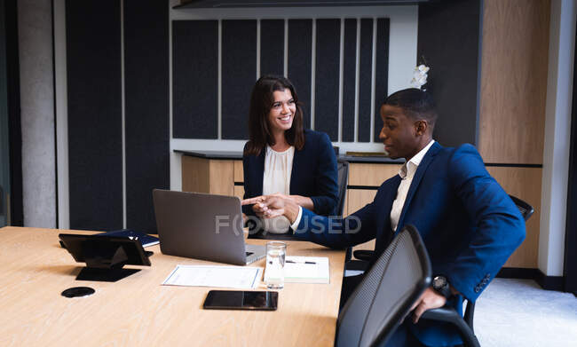 Diverse businessman and businesswoman discussing over laptop in meeting room at modern office. business and office concept — Stock Photo