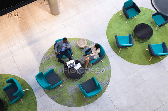 Vista aérea de diversos hombres de negocios y mujeres de negocios discutiendo juntos en la oficina moderna. concepto de negocio y oficina - foto de stock