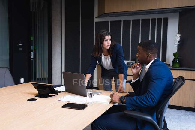 Diverse businessman and businesswoman discussing over laptop in meeting room at modern office. business and office concept — Stock Photo
