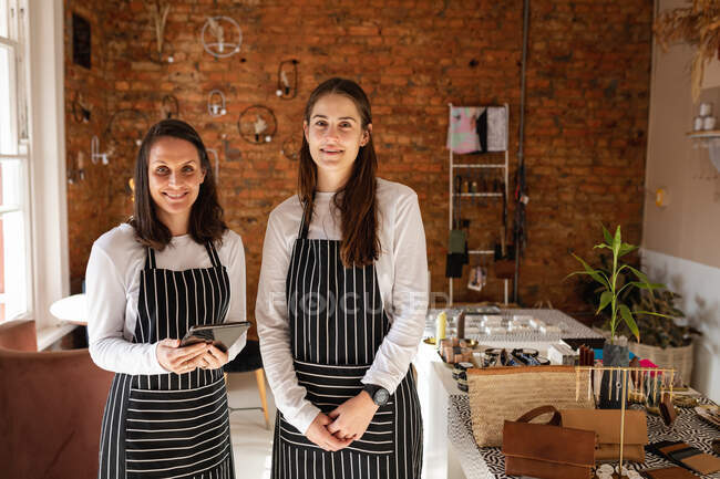 Kaukasische Geschäftsinhaberin und Kellnerin tragen Schürzen, schauen in die Kamera, lächeln. kleines unabhängiges Café-Geschäft. — Stockfoto