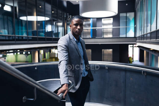 Porträt eines afrikanisch-amerikanischen Geschäftsmannes, der auf der Treppe eines modernen Büros steht. Geschäfts- und Bürokonzept — Stockfoto