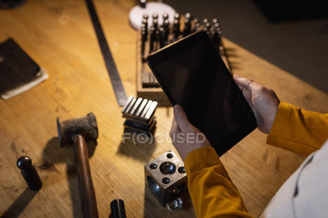 Großaufnahme der Hände einer Juwelierin, die ein Tablet mit Kopierplatz auf dem Bildschirm hält. Selbstständiger Handwerksbetrieb. — Stockfoto