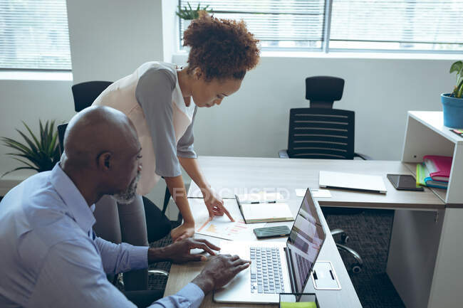 Dois colegas de negócios masculinos e femininos diversos sentados na mesa e usando laptop. trabalhar em um negócio criativo independente. — Fotografia de Stock